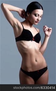 Beautiful brunette woman, model of fashion, wearing black underwear. Young girl in lingerie. Studio shot.
