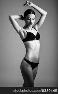 Beautiful brunette woman, model of fashion, wearing black underwear. Young girl in lingerie. Studio shot.