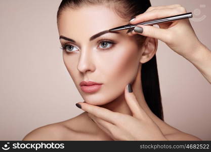 Beautiful brunette woman paints the eyebrows. Beautiful woman face. Makeup detail. Beauty girl with perfect skin