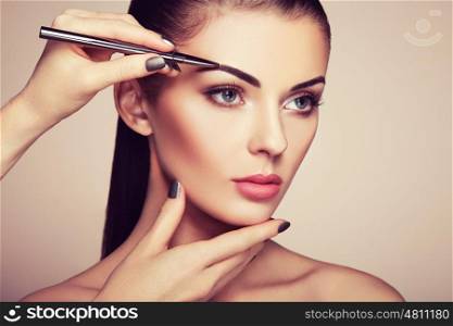Beautiful brunette woman paints the eyebrows. Beautiful woman face. Makeup detail. Beauty girl with perfect skin