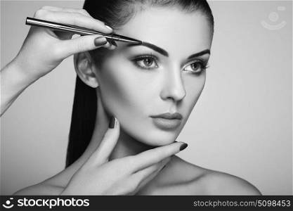 Beautiful brunette woman paints the eyebrows. Beautiful woman face. Makeup detail. Beauty girl with perfect skin. Black and White photo