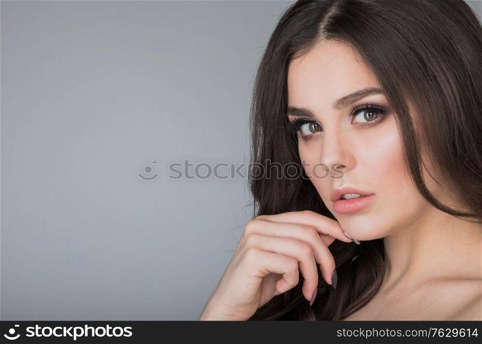 Beautiful brunette woman portrait, healthy hair, clear fresh skin, girl on gray background with copy space for text, skincare, spa, beauty model. Beautiful brunette woman portrait