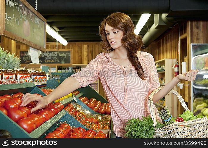 Beautiful brunette woman shopping for tomatoes in supermarket