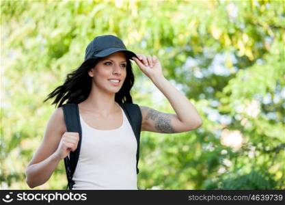 Beautiful brunette woman with cap and backpack hiking