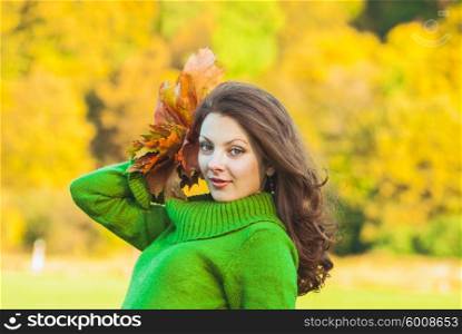 Beautiful brunette woman with maple leaves, autumnal background with copy space