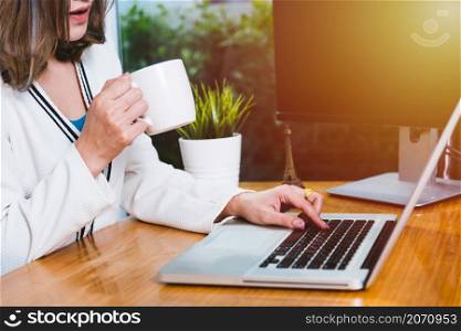 Beautiful business woman lifestyle working using laptop computer and hold coffee cup on hand