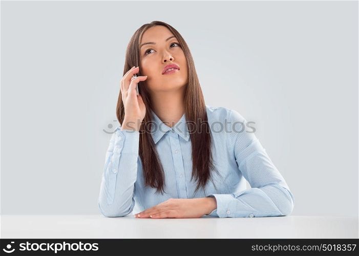 Beautiful business woman talking on cell phone while looking at copyspace at her desk