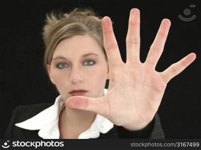 Beautiful Business Woman with Hand Palm Out in Front of Her. Shot in studio over black. Focus on hand.
