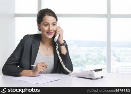 Beautiful businesswoman answering telephone at office desk