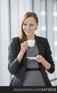 Beautiful businesswoman drinking coffee in office