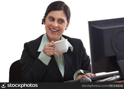 Beautiful businesswoman looking at computer with coffee cup