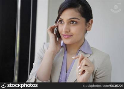Beautiful businesswoman smiling while using mobile phone in office