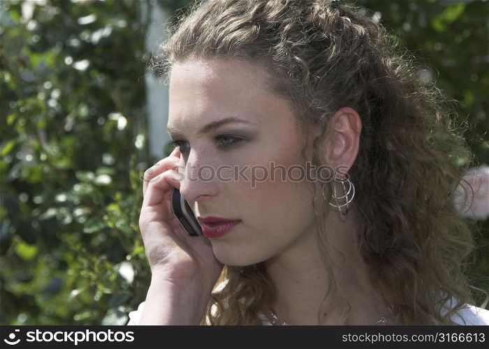 Beautiful businesswoman talking on the phone outdoors during her lunchbreak in the park