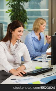 Beautiful businesswoman using computer with colleague at office desk