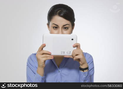 Beautiful businesswoman using digital tablet against gray background