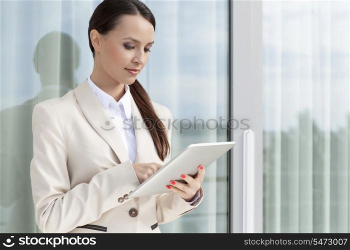 Beautiful businesswoman using digital tablet by glass door