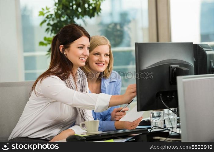 Beautiful businesswomen looking at computer monitor in office