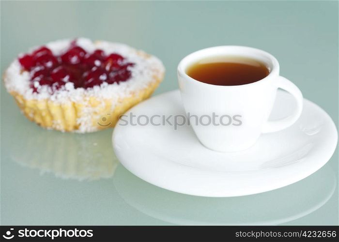 beautiful cake with berries and tea on glass table