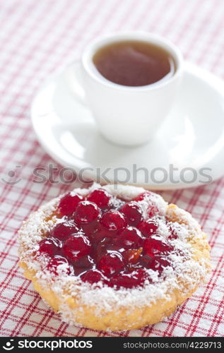 beautiful cake with berries and tea on plaid fabric