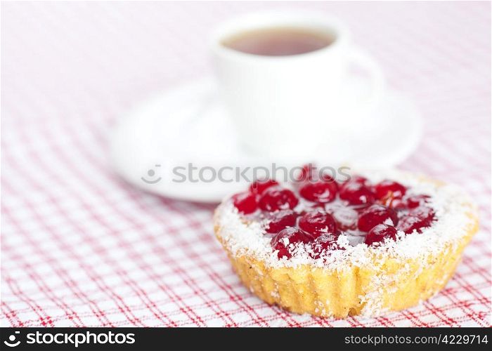 beautiful cake with berries and tea on plaid fabric