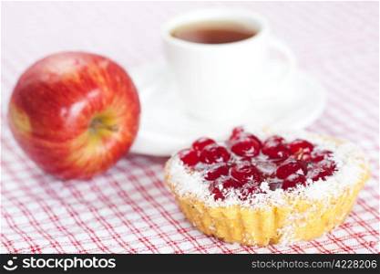 beautiful cake with berries,apple and tea on plaid fabric