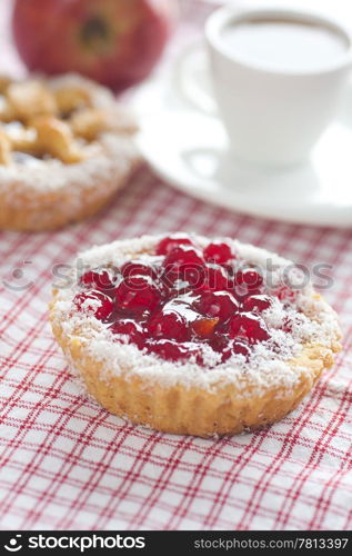 beautiful cake with berries,apple and tea on plaid fabric