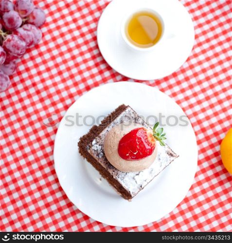 beautiful cake with strawberry,tangerine,grape and tea on plaid fabric