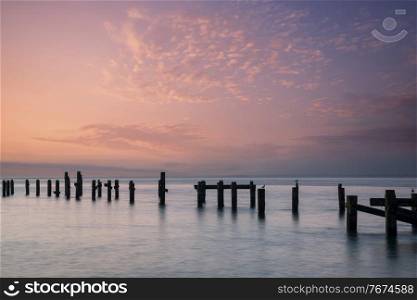 Beautiful calm sea landscape of old derelict pier foundations at sunrise