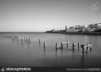 Beautiful calming long exposure landscape of ruined pier at sunset
