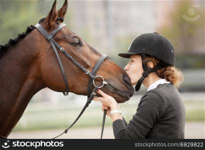 Beautiful Candid Portrait of a Happy Teenager Kissing a snout of her Horse Outdoors