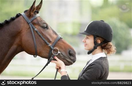 Beautiful Candid Portrait of a Happy Teenager Looking with Love at her Horse Outdoors