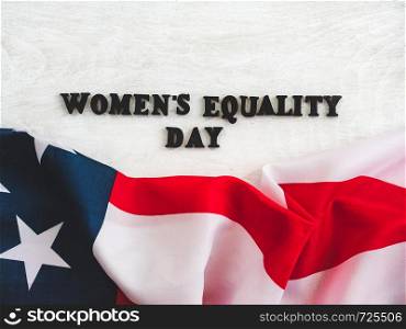 Beautiful card for Women's Equality Day. Wooden letters with a congratulatory inscription on a white background. Close-up, top view. Congratulations for loved ones, relatives, friends and colleagues. Beautiful, bright greeting card with a holiday