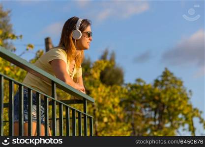 beautiful casual woman enjoying music at the sunset, with headphones, outdoor