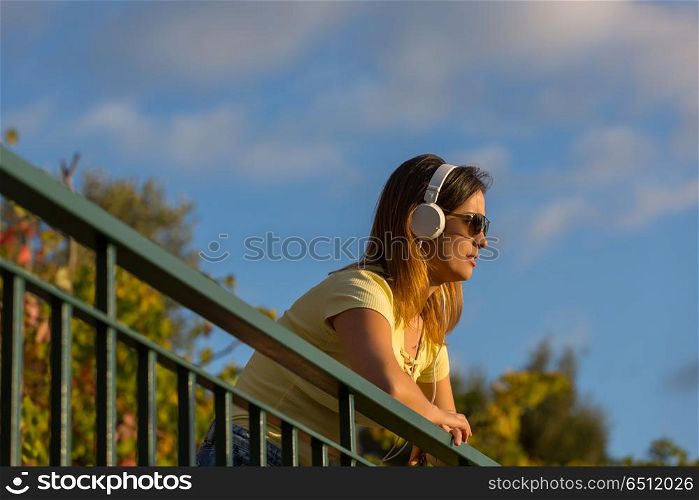 beautiful casual woman enjoying music at the sunset, with headphones, outdoor. sunset
