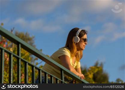 beautiful casual woman enjoying music at the sunset, with headphones, outdoor. sunset