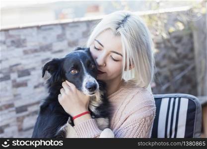 Beautiful caucasian girl hugging her dog pet sitting on chair at home terrace