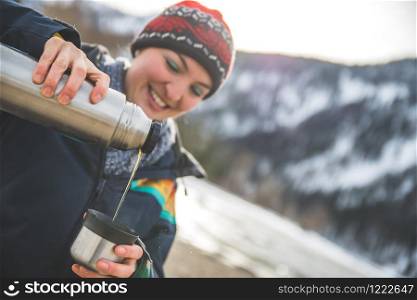 Beautiful Caucasian girl is holding a cup of tea outdoors, winter time
