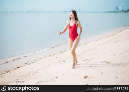 Beautiful Caucasian woman in red swimsuit is running on the beach
