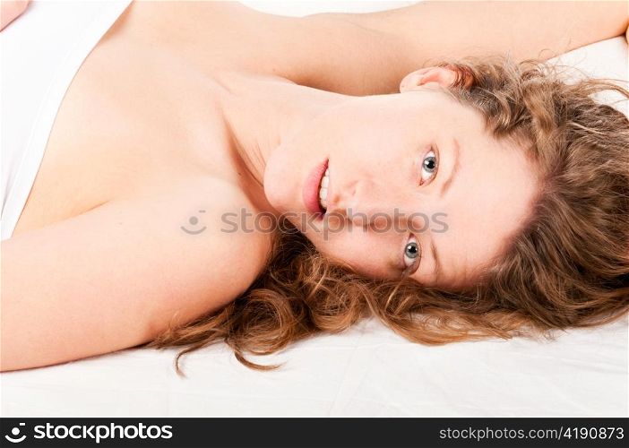 beautiful caucasian woman is lying in bed and looking at camera at morning