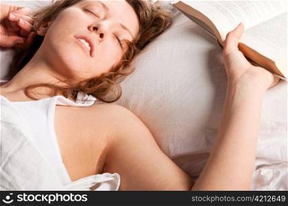 beautiful caucasian woman is lying in bed at morning and holding open book