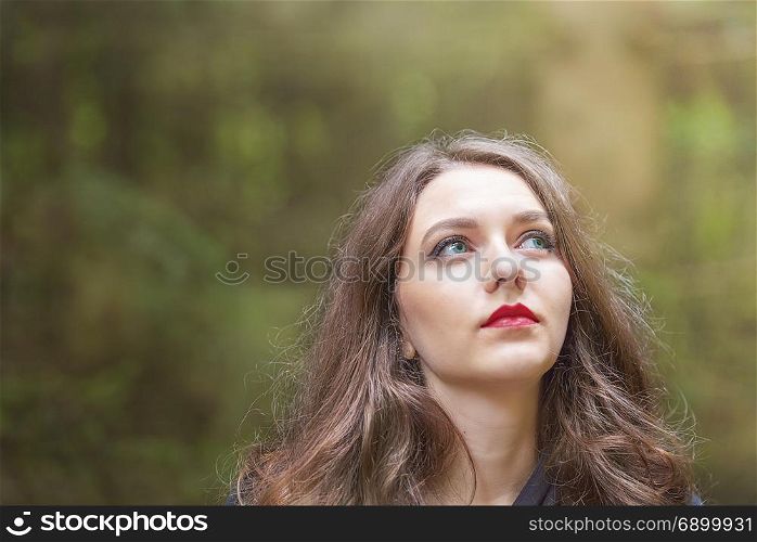 Beautiful caucasian woman with green eyes and red lips, looking to her left, towards the beam of light.