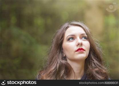Beautiful caucasian woman with green eyes and red lips, looking to her left, towards the beam of light.