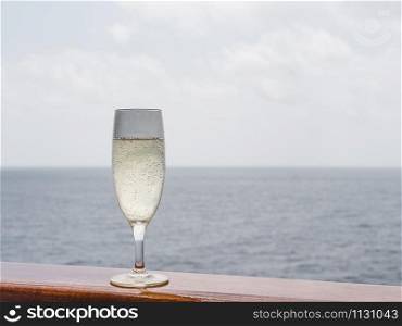 Beautiful champagne glass on the open deck of a cruise liner against the backdrop of blue sea waves. Side view, close-up. Concept of leisure and travel. Beautiful champagne glass on the open deck