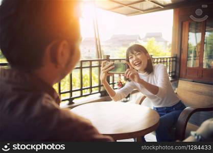 beautiful cheerful asian younger woman taking a photo by smart phone with happiness emotion