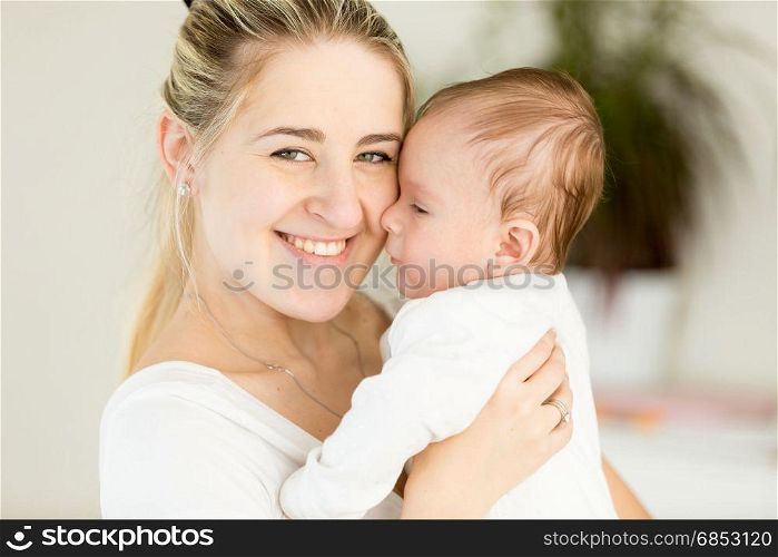 Beautiful cheerful mother embracing her 3 months old baby boy