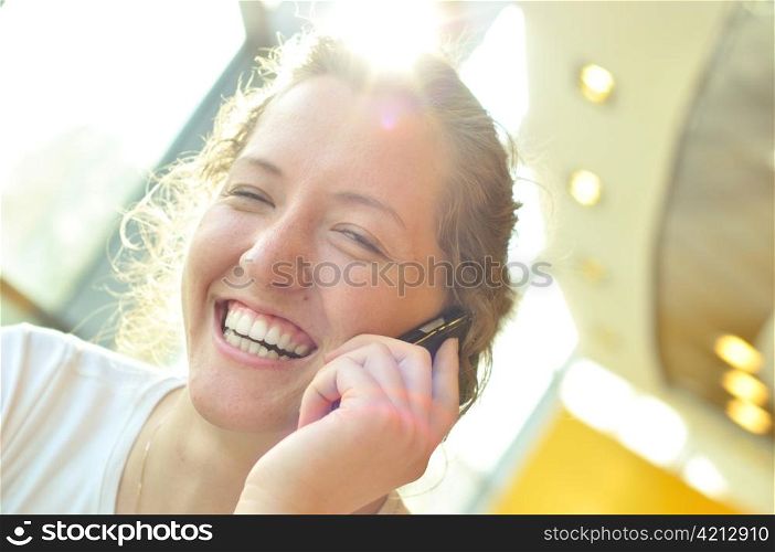 beautiful cheerful woman is talking phone in sunny cafe
