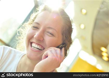 beautiful cheerful woman is talking phone in sunny cafe