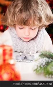 Beautiful child blowing out Christmas candles