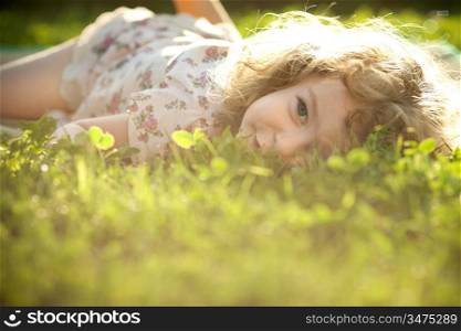 Beautiful child lying on a grass on a spring meadow in sunshine