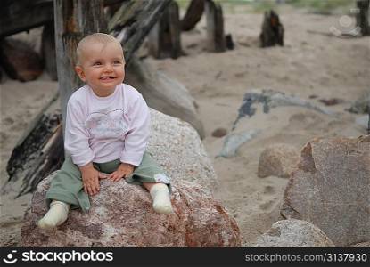 beautiful child sits on stone at sea